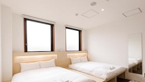 Una habitación de hotel con dos camas individuales, un espejo grande y una ventana con persianas.
