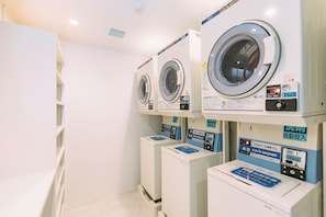 A row of stacked front-loading washing machines in a commercial setting. - WeBase KYOTO - Hostel (Kyoto)