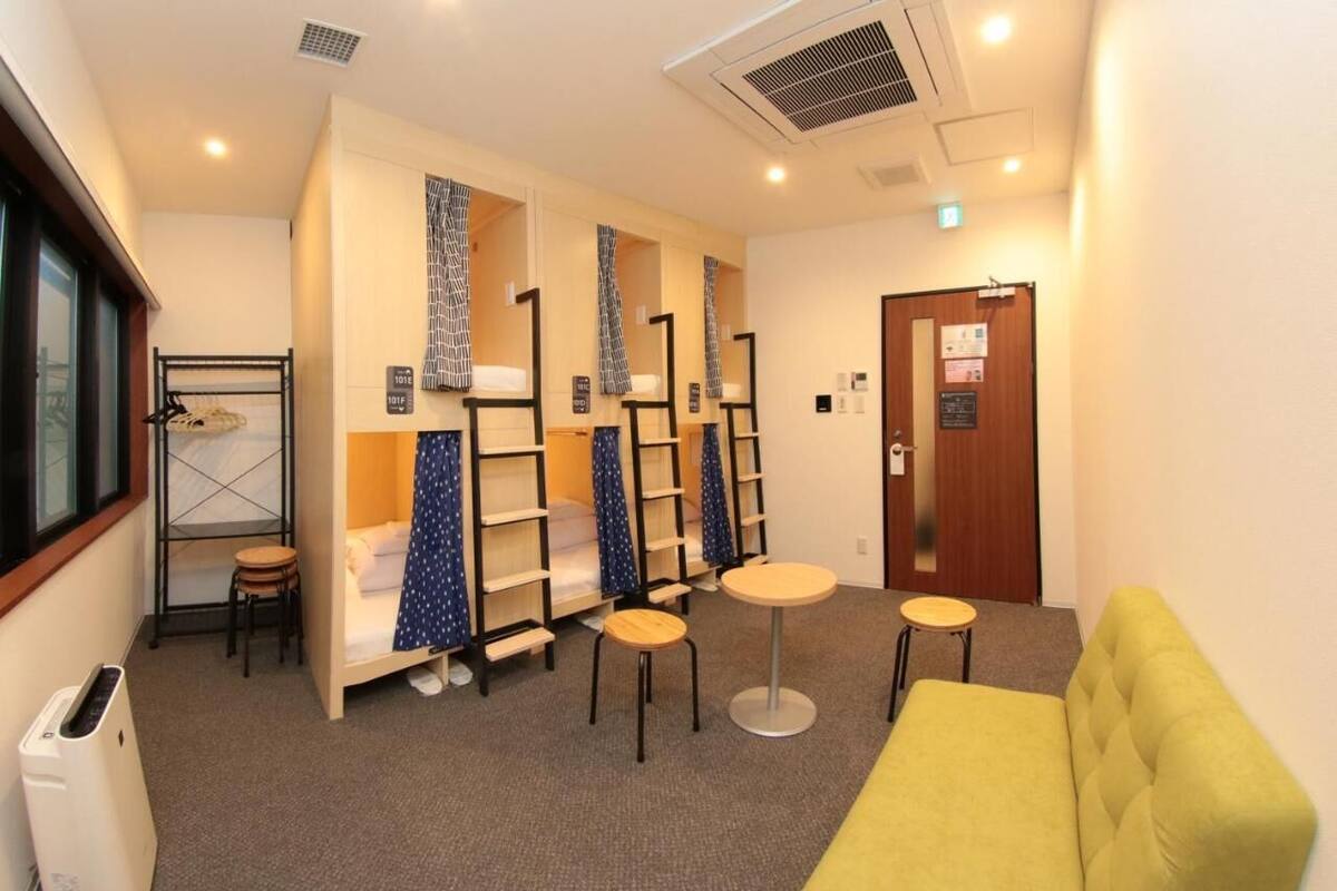 A hotel room with bunk beds, a yellow sofa, and a small round table.