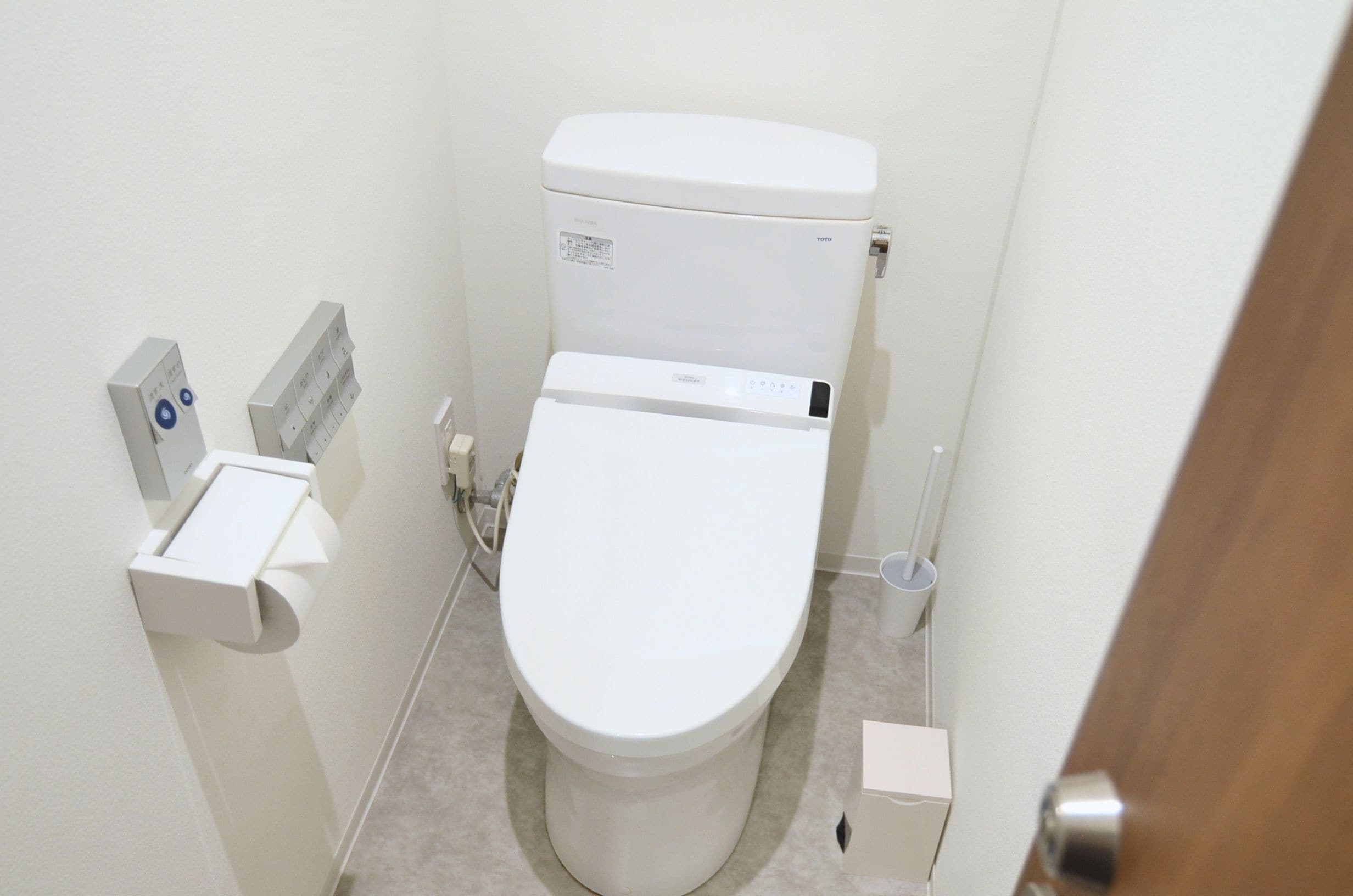 A small, modern bathroom with a toilet, a bidet, and a hand dryer.