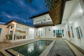 Ein modernes Haus mit Schwimmbad, Küchenbereich und Essbereich.