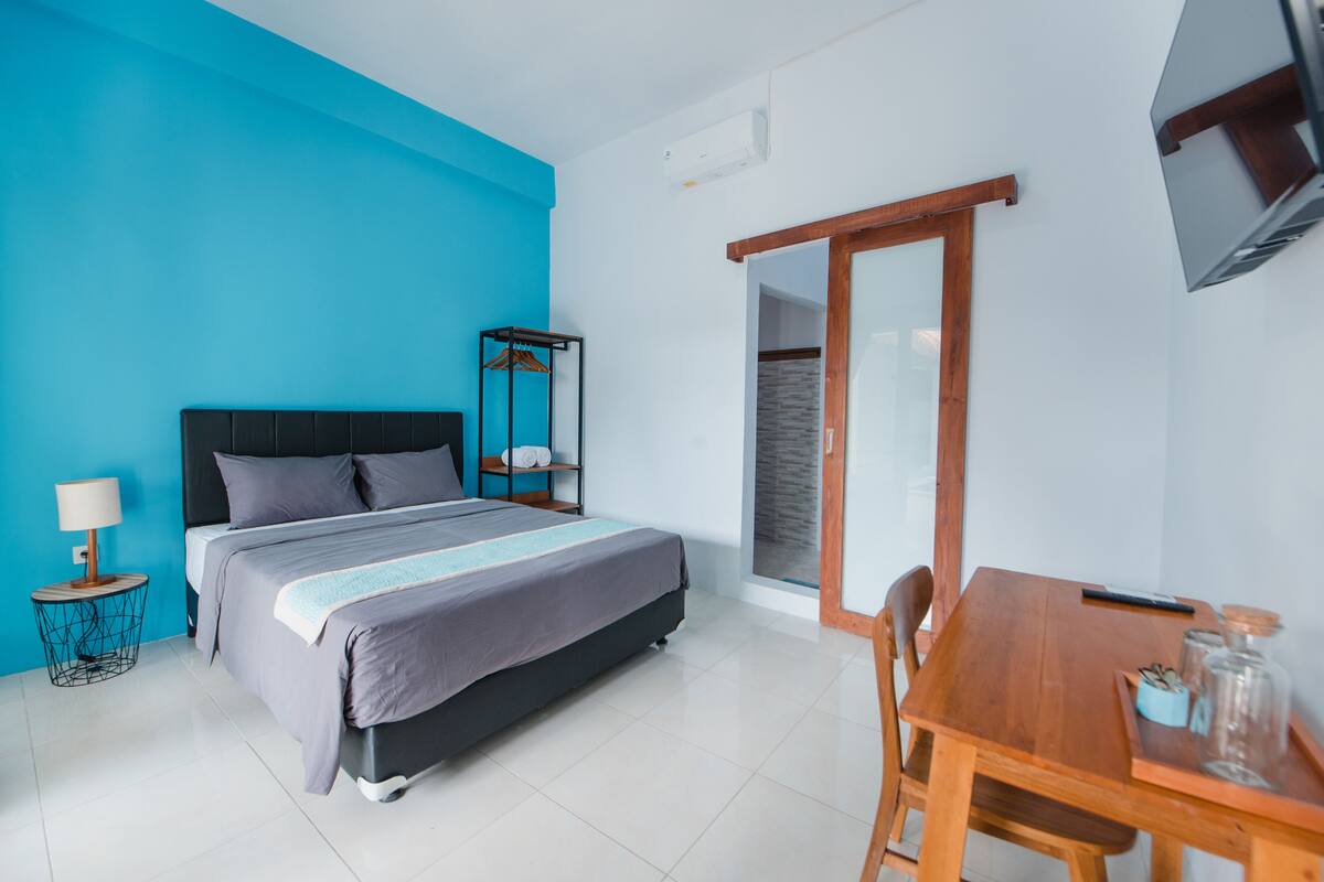A modern bedroom with a bed, bedside table, and a wooden dining table.