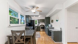 Ett modernt kök med trägolv, en matplats med bord och stolar samt en takfläkt.