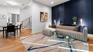 A modern living room with a sofa, coffee table, and a rug with directional arrows. - Spacious 3BR Townhome with Majestic Rooftop Views (Atlanta)
