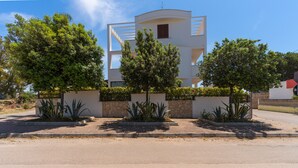 A modern building with a curved facade, surrounded by well-maintained landscaping and a paved driveway.