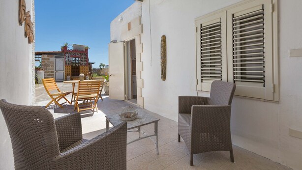 An outdoor patio with wicker furniture, a table, and a view of a building with a gate and a door. - 2432 Tenuta Fioravante - Bilo Antonia by Barbarhouse (Porto Cesareo)