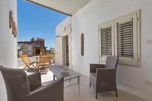 An outdoor patio with wicker furniture, a table, and a view of a building with a gate and a door. - 2432 Tenuta Fioravante - Bilo Antonia by Barbarhouse (Porto Cesareo)
