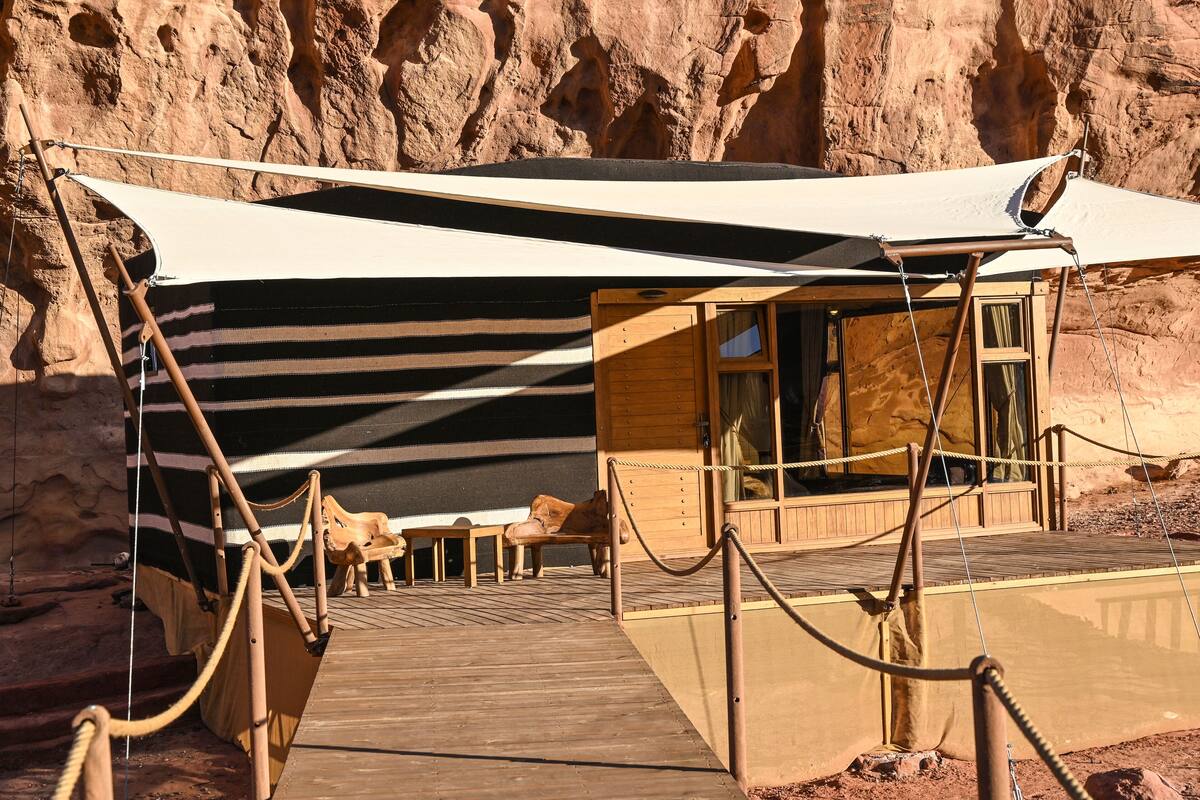 Tenda no deserto com deck de madeira, toldo listrado e uma barreira de corda.