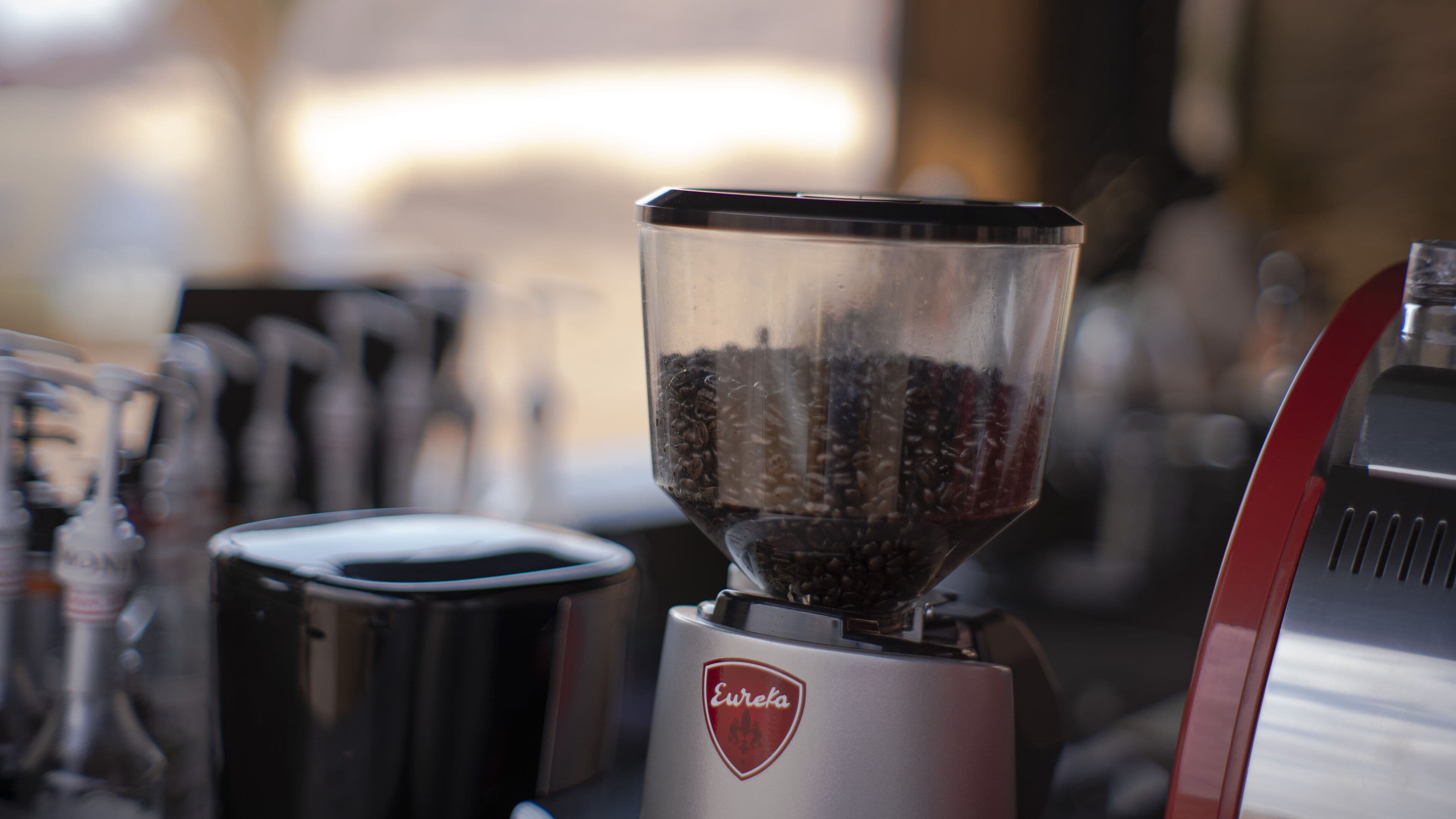 A coffee grinder with a transparent container filled with coffee beans.