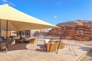 Un área de estar al aire libre con muebles de madera y un toldo grande.