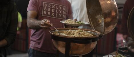 A person serving food from a large copper pot.