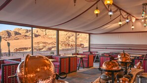 Un comedor con vistas al desierto, asientos de estampado rojo y utensilios de cocina de cobre.