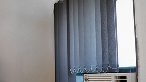 Una ventana con cortinas oscuras y un equipo de aire acondicionado blanco.
