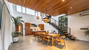 Een ruim interieur met een houten eettafel, stoelen, een keukenhoek en een trap.