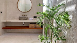 Een badkamer met een ronde spiegel, een wastafel en een plant.