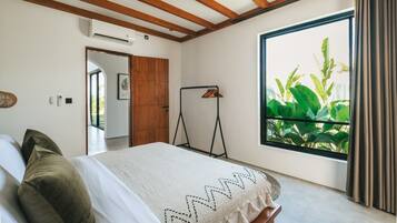 A bedroom with a bed, a ceiling fan, a window with curtains, and a view of greenery outside.