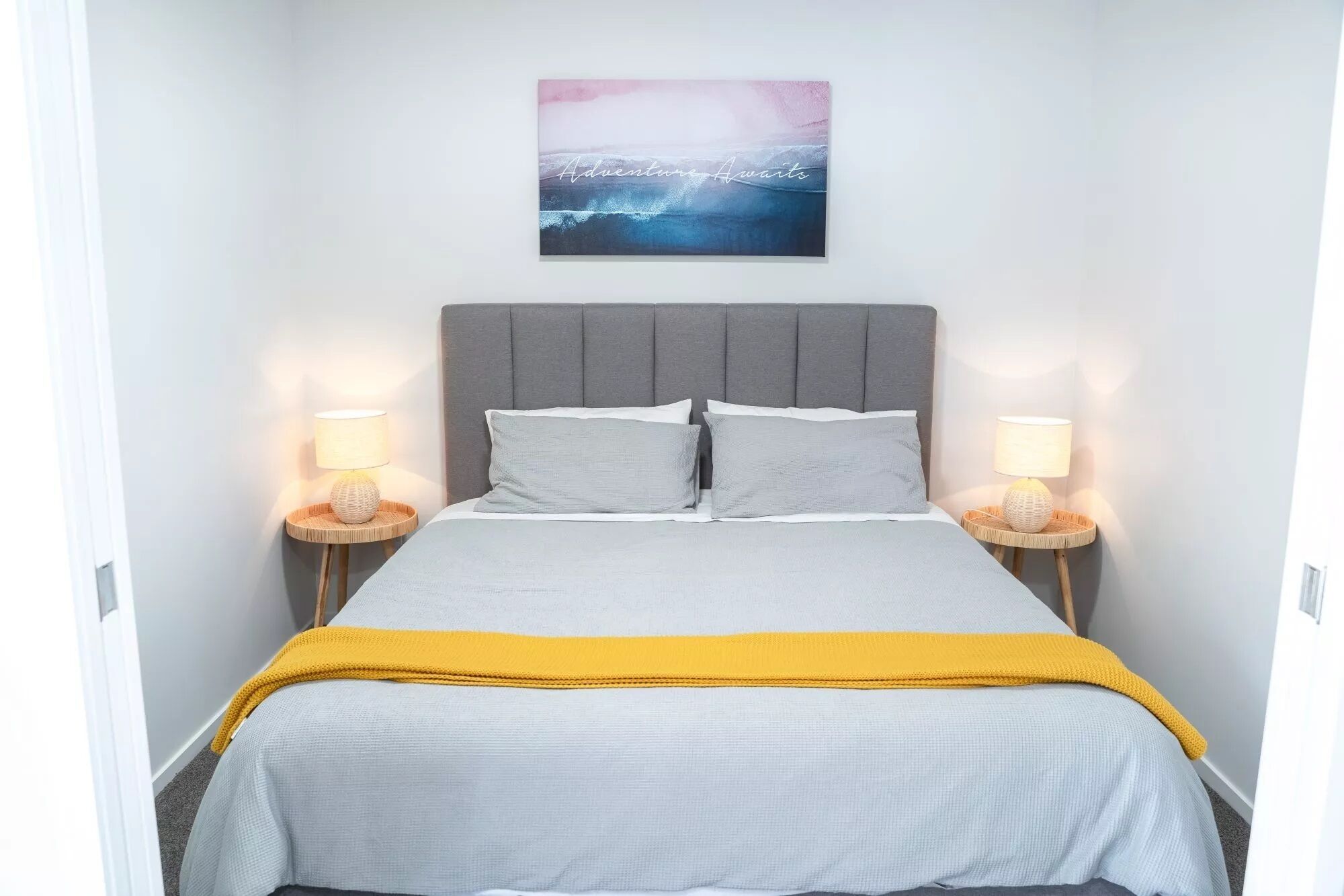 Une chambre à coucher comprenant un lit, deux lampes de chevet, une tête de lit et une œuvre d’art accrochée au mur.