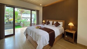 A modern bedroom with a large bed, two bedside tables with lamps, a sliding glass door to a balcony, and a view of greenery outside. - Sulendra Jungle Suites Ubud View by EPS (Ubud)