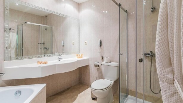 Een moderne badkamer met een douchecabine van glas, een witte wastafel en een toilet.