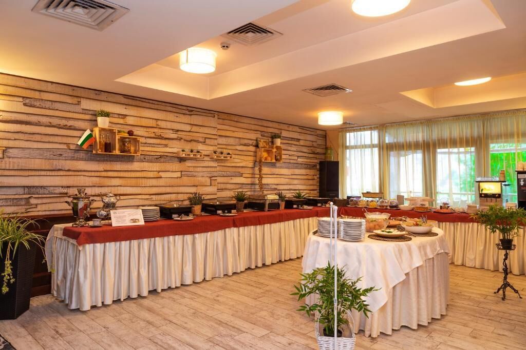 Uma sala de conferências com uma mesa comprida posta para um buffet, paredes de painel de madeira e janelas grandes com cortinas.