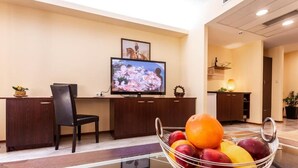 A reception area with a TV, a desk, a chair, and a fruit bowl.