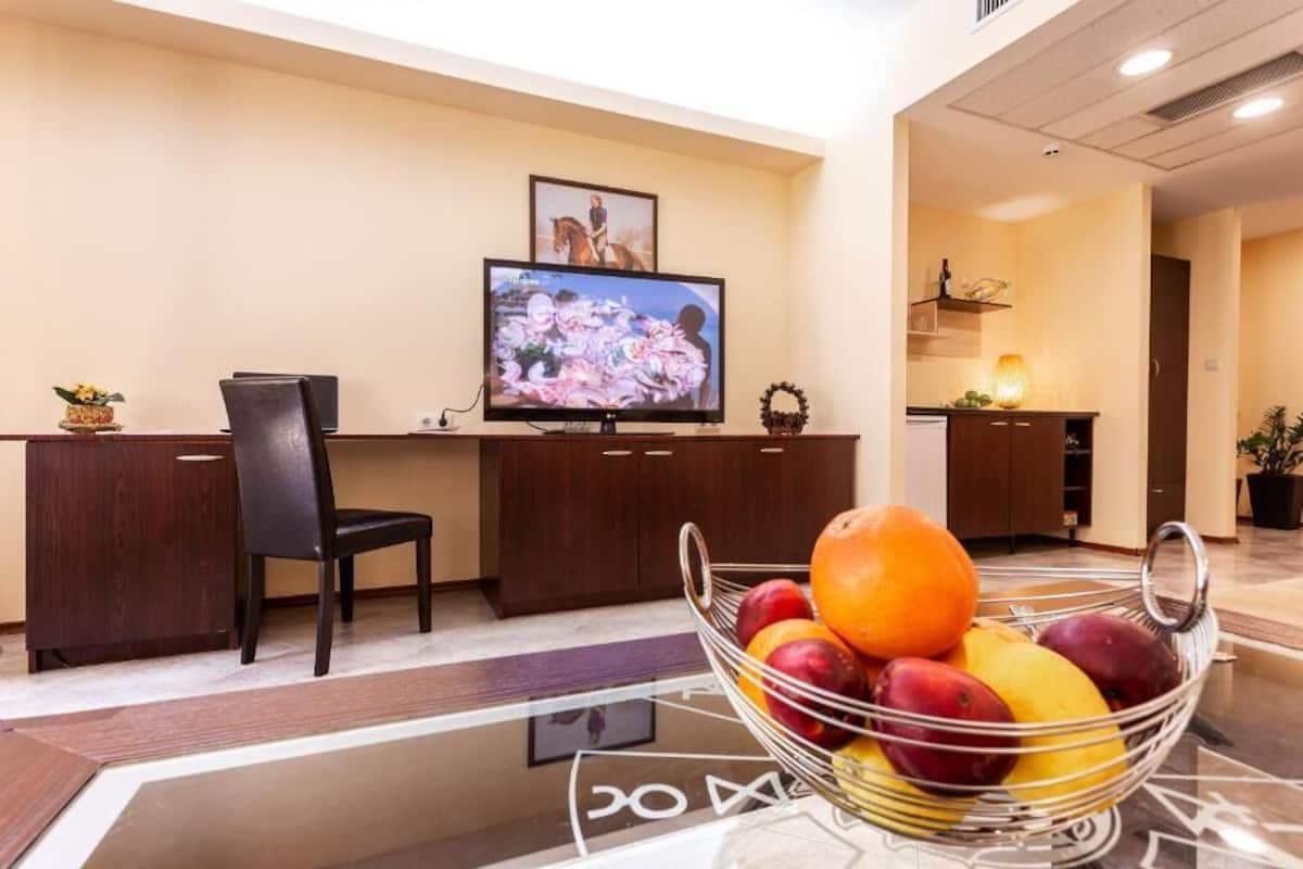 A reception area with a TV, a desk, a chair, and a fruit bowl.