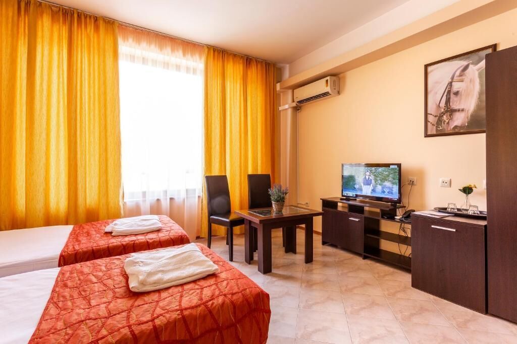 A hotel room with two beds, a TV, a desk, and a cabinet.