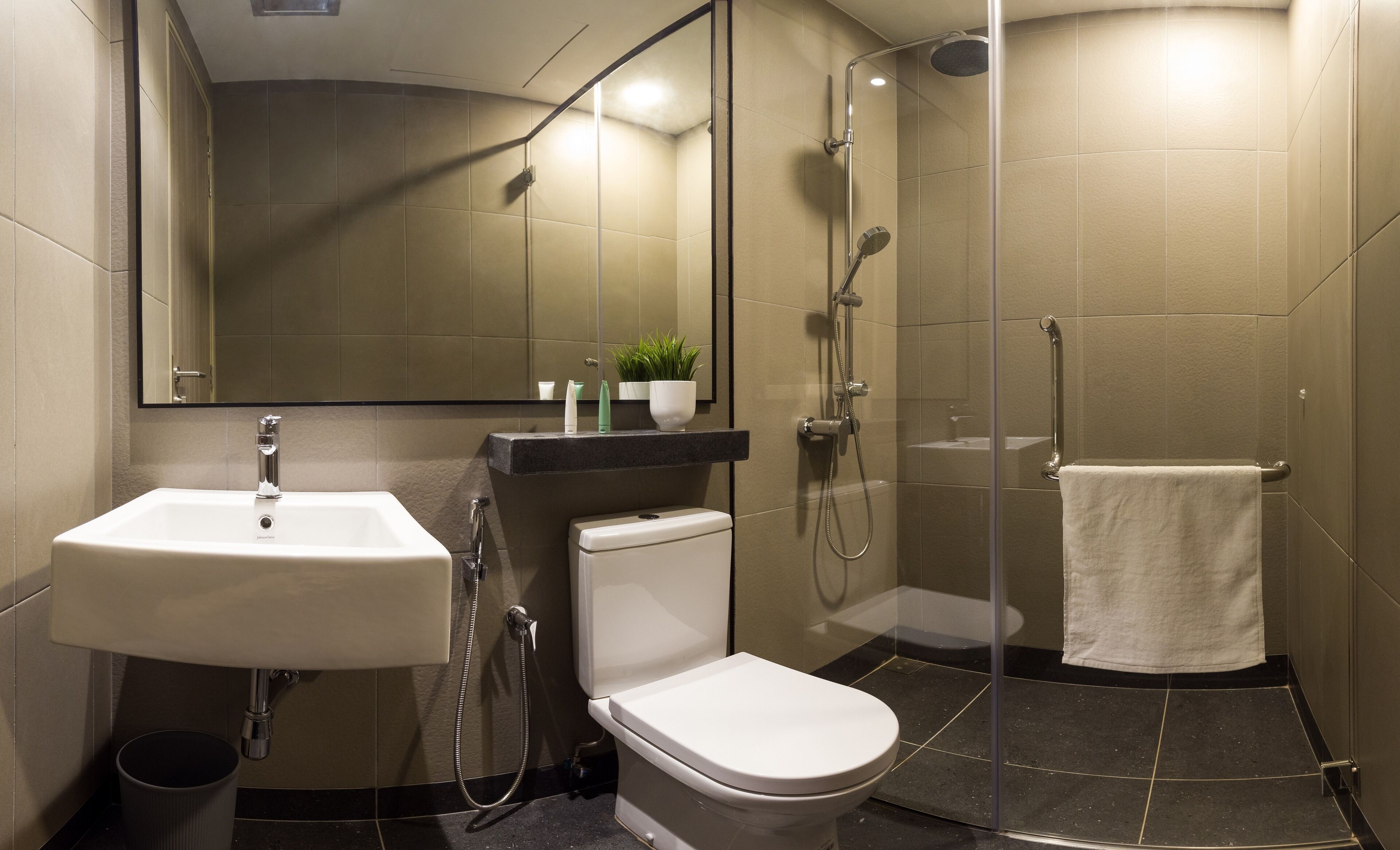 Un baño moderno con lavamanos, inodoro y ducha.