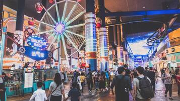 Un área de entretenimiento cubierta concurrida, con una noria, diversas atracciones y una multitud de gente.