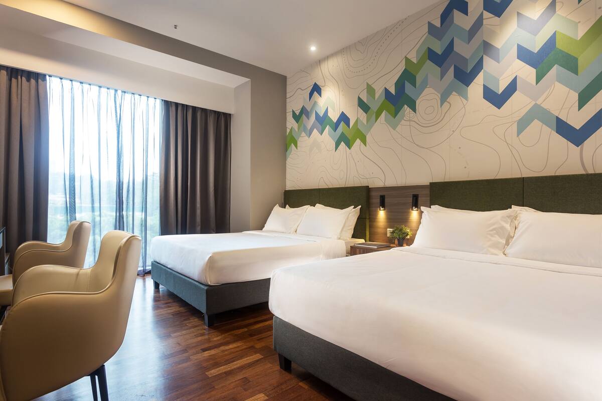 Une chambre d’hôtel avec deux lits, un bureau et une chaise.