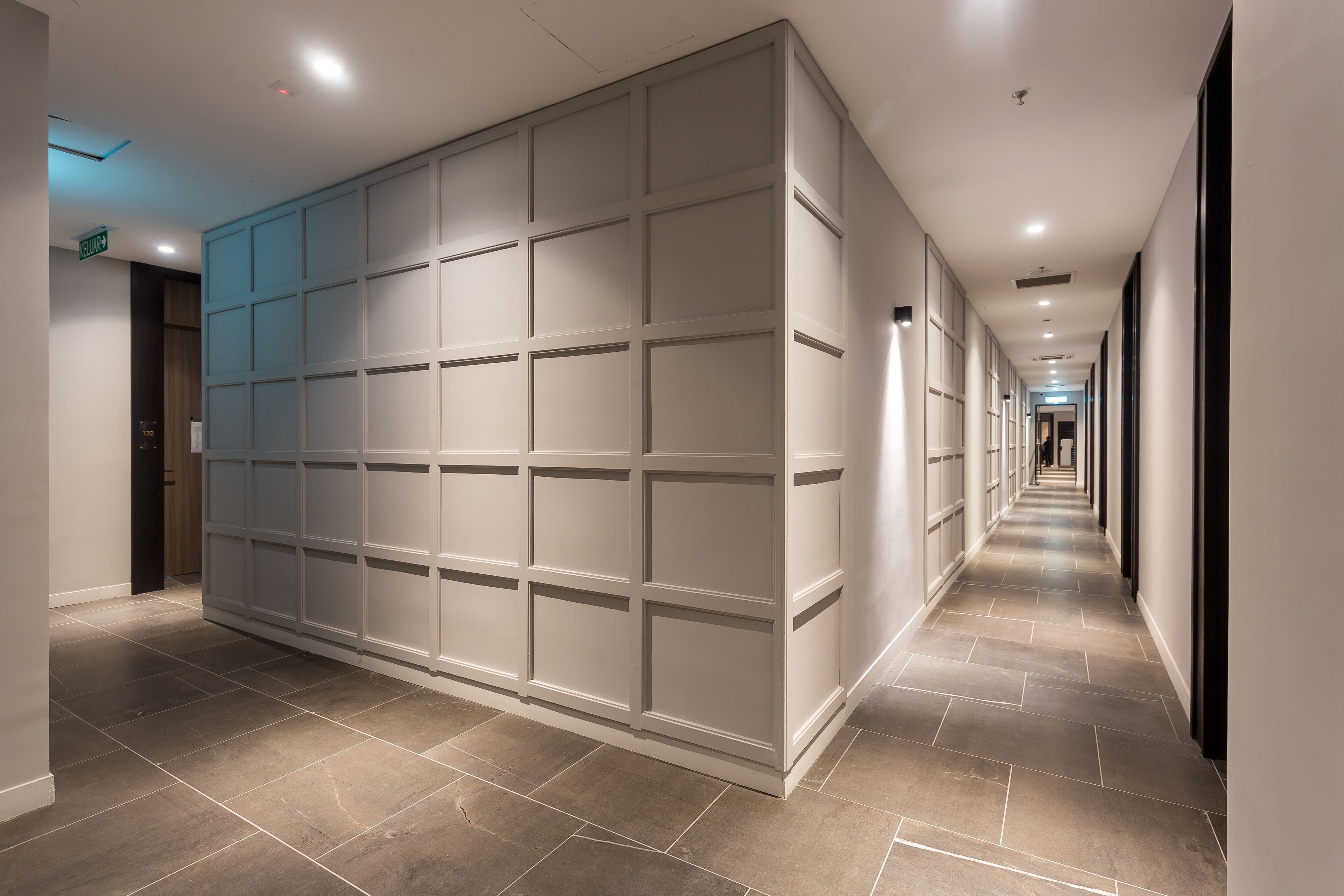 A hallway with a tiled floor and a large, white, paneled wall.