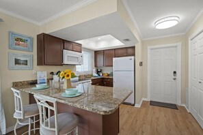 A kitchen with granite countertops, a refrigerator, and a microwave. - Bayfront Complex | Walk to Beach | Dock Slip (Sarasota)