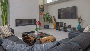A modern living room with a fireplace, a flat-screen TV, and a sofa. - The Downtown Anchorage Grand Four Bedroom (Anchorage)