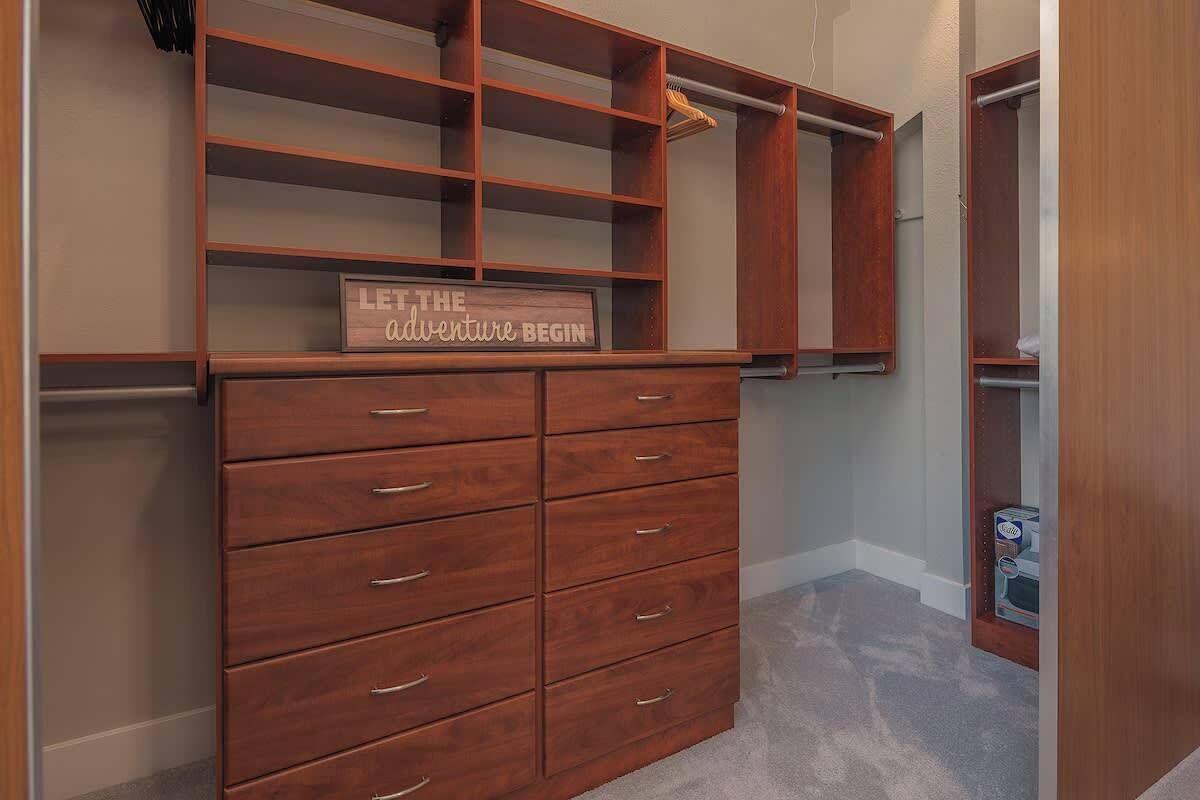 A wooden dresser with multiple drawers and shelves, a mirror, and a sign that reads "LET THE ADVENTURE BEGIN".