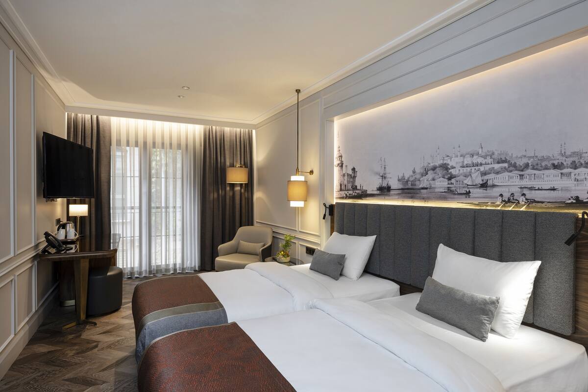 A hotel room with a large bed, a desk, a chair, and a TV.