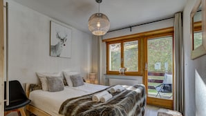 A bedroom with a wooden bed, a fur throw, a deer painting, and a large window.