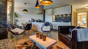 A modern living room with a dining area, kitchen, and stone accent wall.