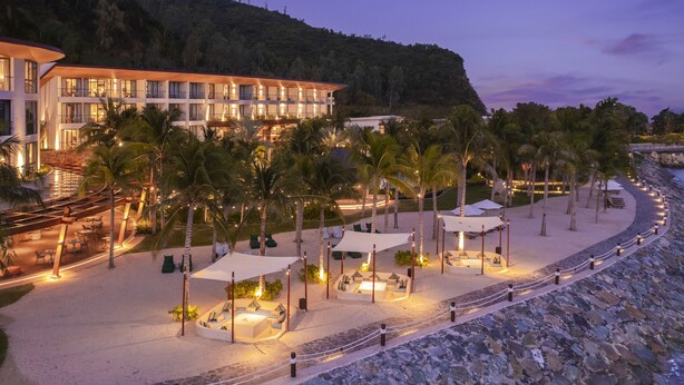 Un hotel frente a la playa con varios balcones, zonas de estar al aire libre y vista a la playa y al océano.