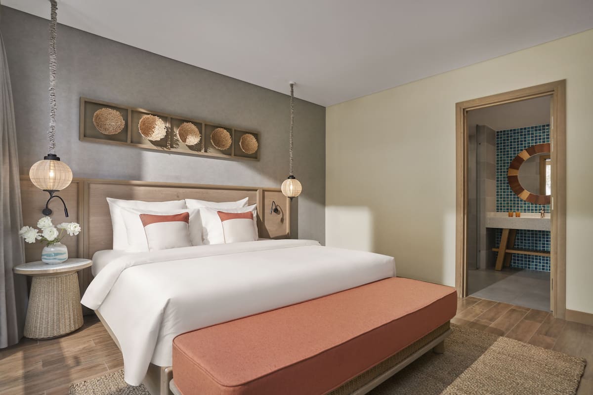 Une chambre à coucher bien aménagée, avec un grand lit, des tables de chevet et une œuvre d’art accrochée au mur.