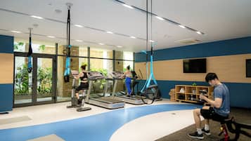 A gym with treadmills, a stationary bike, and a yoga ball. There is a bench and a shelf with items on it.