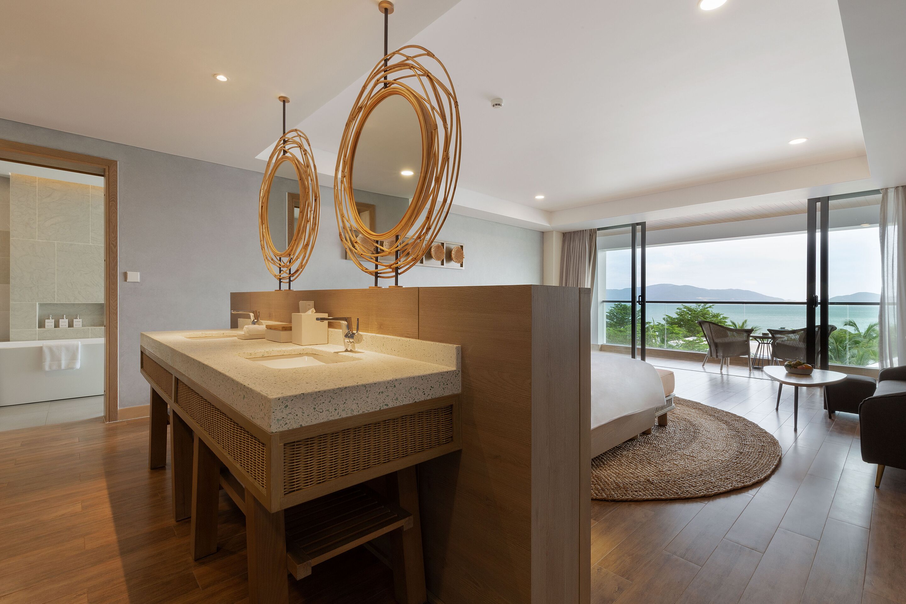A modern bathroom with a large sink, two mirrors, and a view of the ocean.