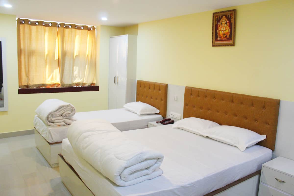 Habitación de hotel con dos camas, una ventana con cortinas, un armario y un cuadro colgado en la pared.