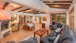 Amplia sala de estar con chimenea, mesa de comedor y sofá de cuero.