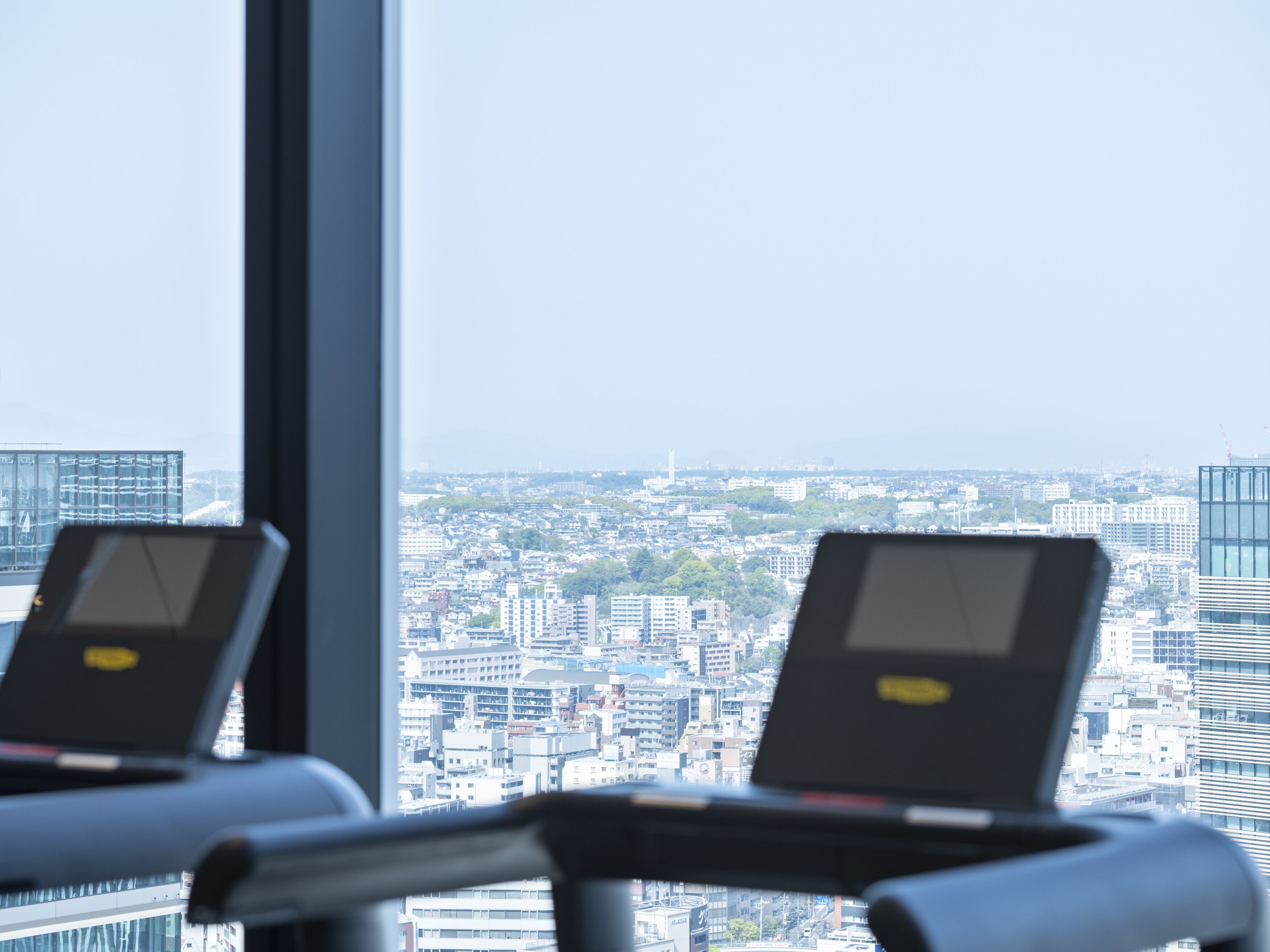 A treadmill in a room with a large window overlooking a cityscape.