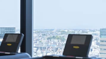 A treadmill in a room with a large window overlooking a cityscape.