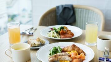 A breakfast setting with plates of food, a croissant, and drinks on a table.