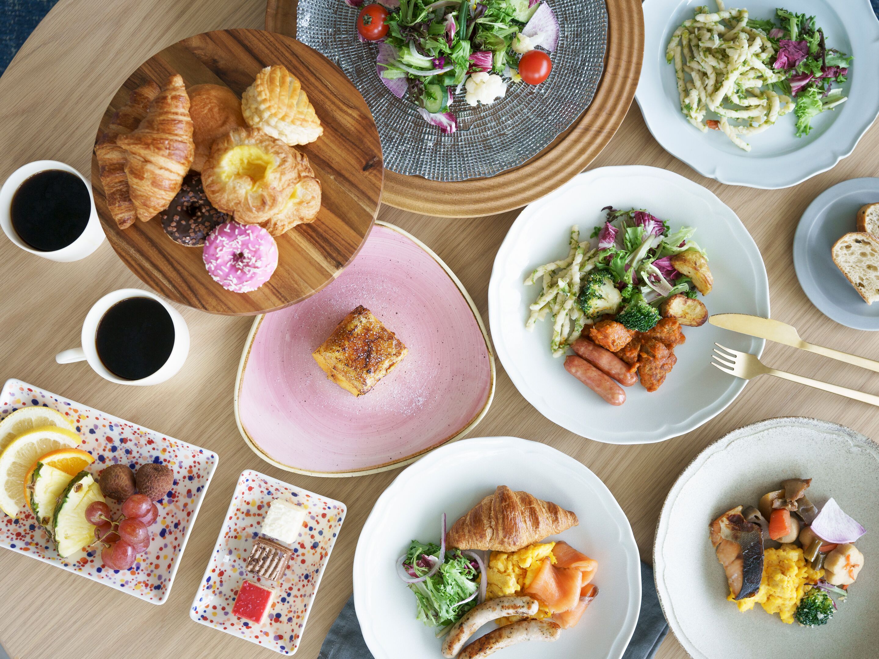A table with various breakfast items including croissants, omelets, and a salad.
