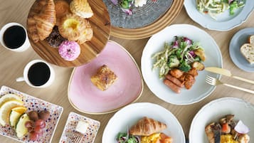 A table with various breakfast items including croissants, omelets, and a salad.