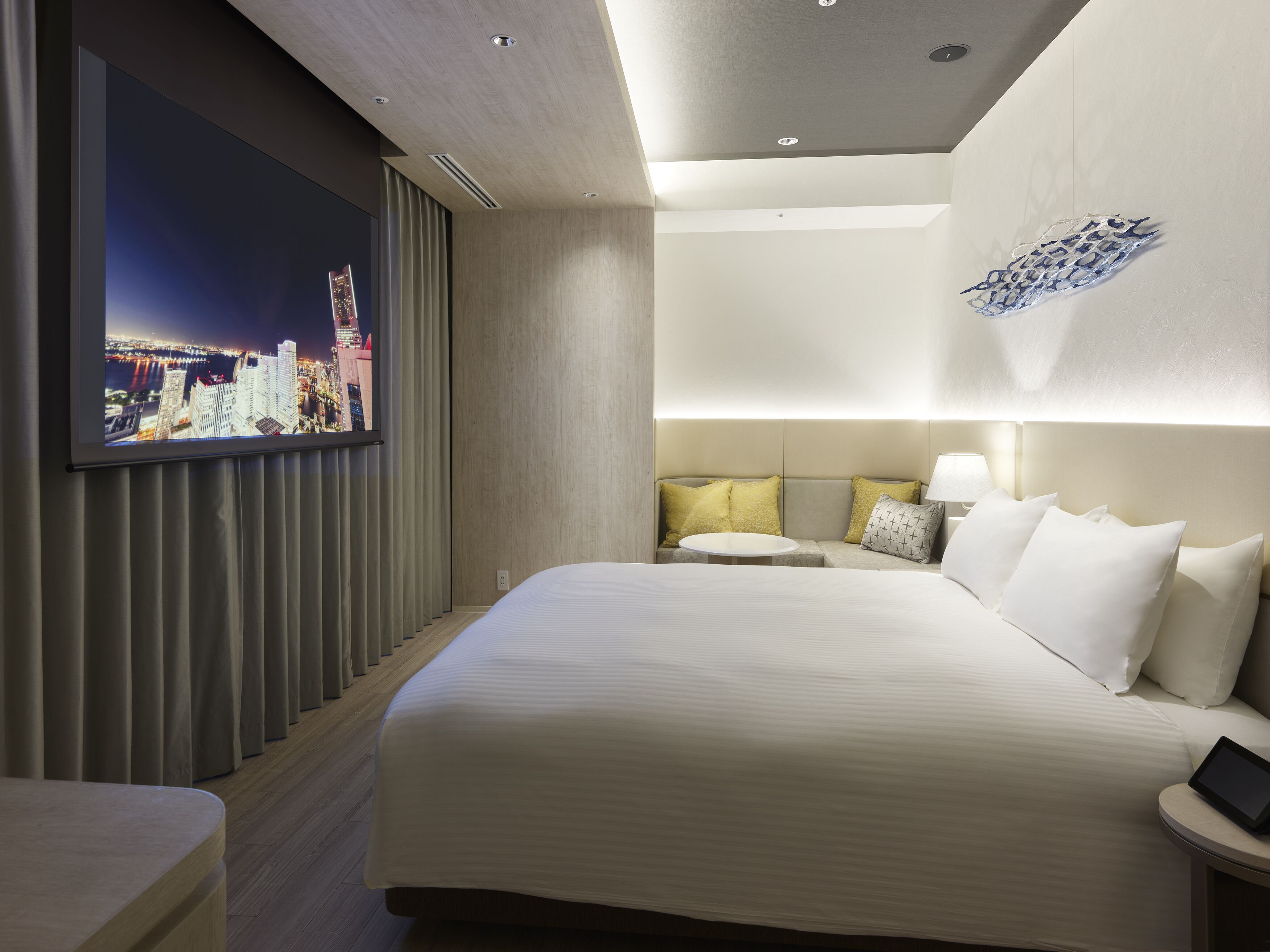Ett modernt hotellrum med en stor säng, en tv som är monterad på väggen och utsikt över staden.