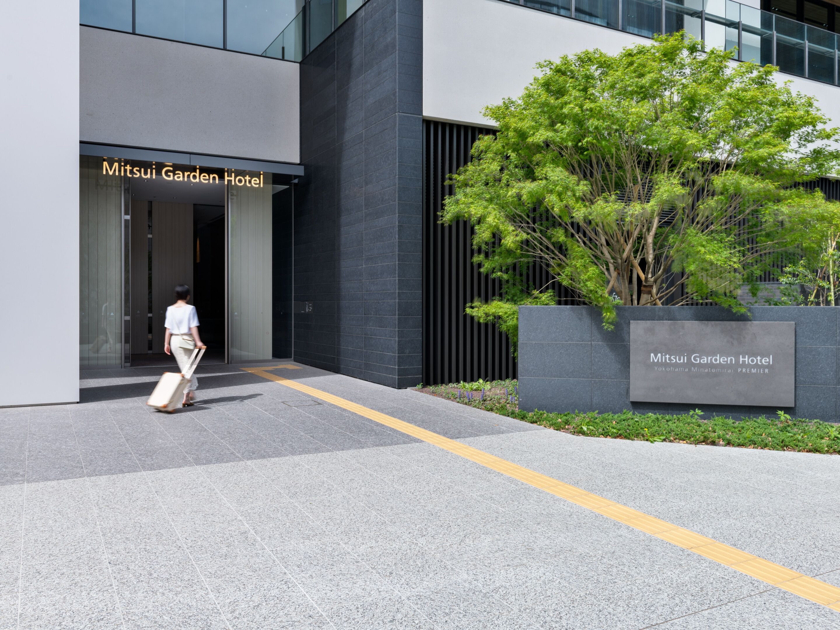 The entrance of Mitsui Garden Hotel with a clear pathway and a signboard.